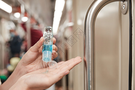 地铁带口罩地铁上使用免洗洗手液除菌的女性背景