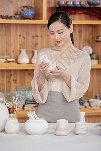 美女陶艺匠人检验陶艺品背景图片
