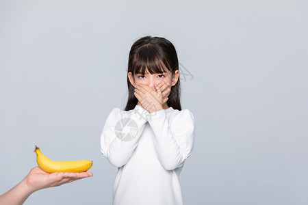小女孩捂着嘴不想吃水果背景图片