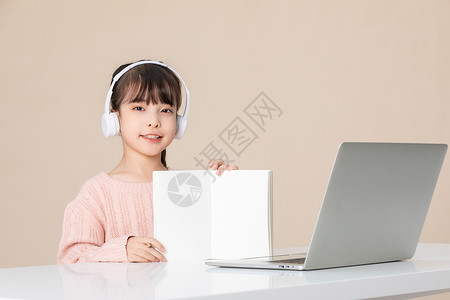 小女孩使用笔记本电脑做笔记背景图片