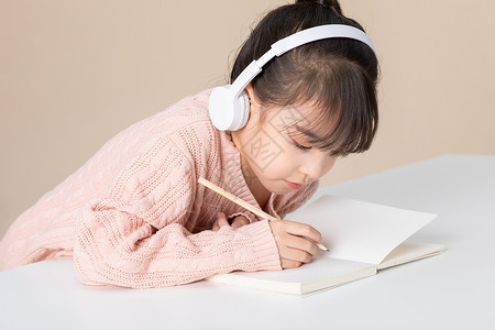 坐在笔上的女孩小女孩趴在桌子上写字做作业近景背景
