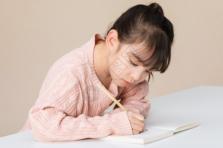 小女孩趴在桌子上认真写字做作业高清图片