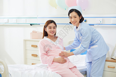 医院产房护士扶着孕妇上病床图片