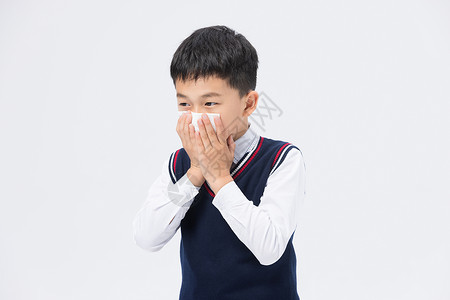 打喷嚏使用纸巾捂住口鼻的小男孩图片