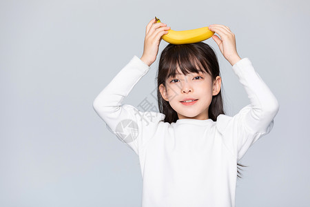 平衡膳食宝塔小女孩把水果香蕉顶在头上背景