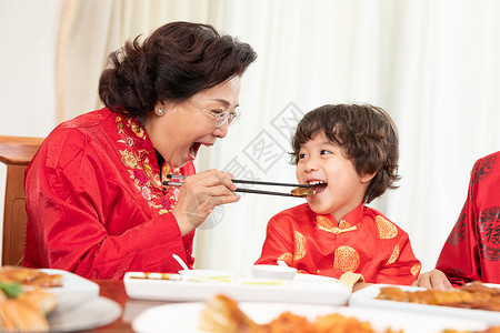 新春年夜饭奶奶夹菜喂小男孩背景图片