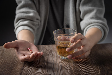 手里拿着药和酒杯的男性特写图片