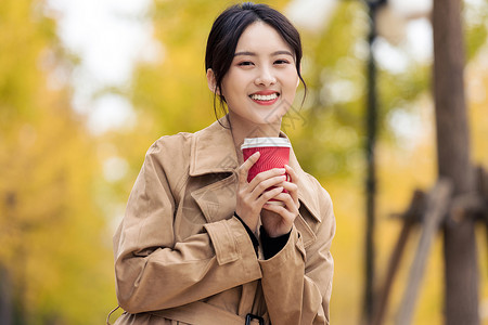 风衣女户外手捧咖啡的知性女青年背景