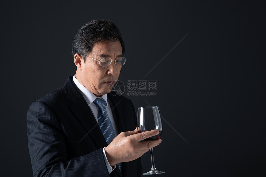 成熟男性低头看手里的酒杯图片
