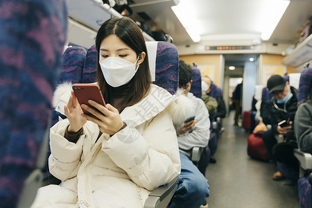 在火车车厢玩手机的女性图片
