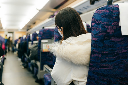 女性坐在火车车厢内四处张望背景