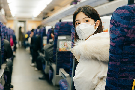 女性坐在火车车厢内以回头看后方背景