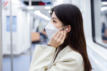 乘坐地铁的女性戴上耳机高清图片