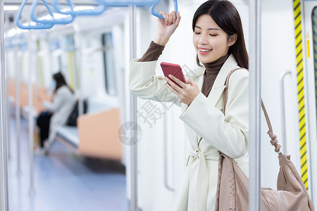 乘坐地铁的女性看着手机笑图片
