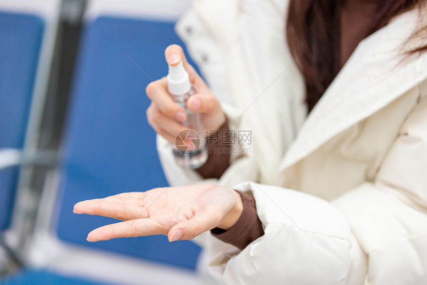 女性使用酒精喷雾给手部消毒图片