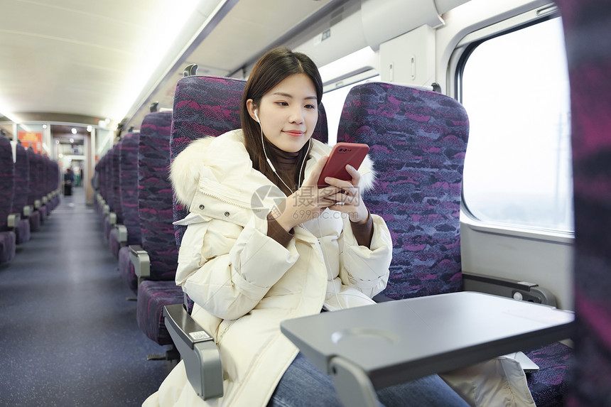 坐在火车上的女性戴着耳机听音乐图片