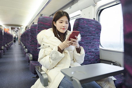 车上看手机坐在火车上的女性戴着耳机听音乐背景