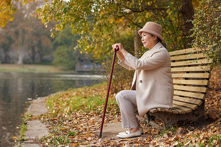 冬季孤单老奶奶公园里湖边休息背景图片
