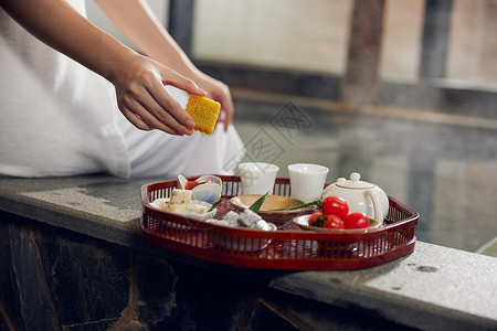 年轻女性泡温泉吃小食图片