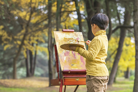 画画的男孩秋季儿童公园里拿调色盘绘画背景