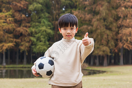 小男孩点赞秋季小男孩公园里抱足球点赞背景