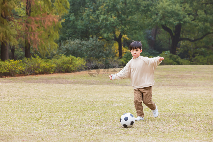 秋季小男孩公园里踢足球图片