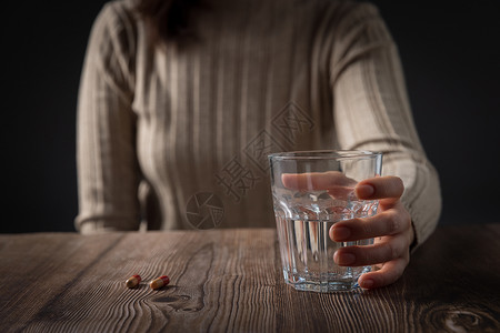 在黑暗中摸索在黑暗中握着酒杯的女性的手背景