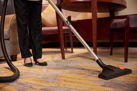 酒店服务人员使用吸尘器清洁地毯特写高清图片
