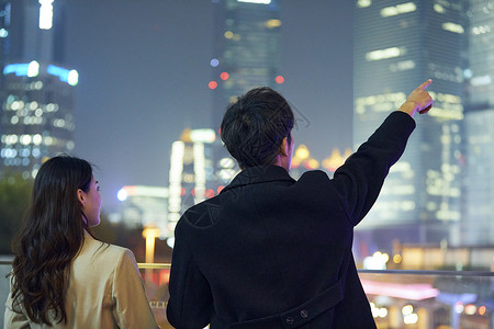 背影夜晚年轻情侣看向夜晚城市背影背景