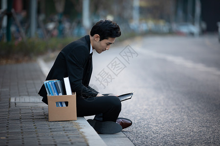 失业被炒鱿鱼的男性坐在街头户外高清图片素材