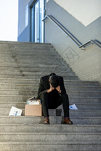 裁员危机被辞退的商务男性失落的坐在楼梯上背景