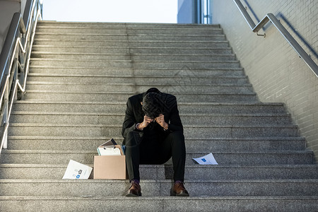 职场沮丧被辞退的商务男性失落的坐在楼梯上背景