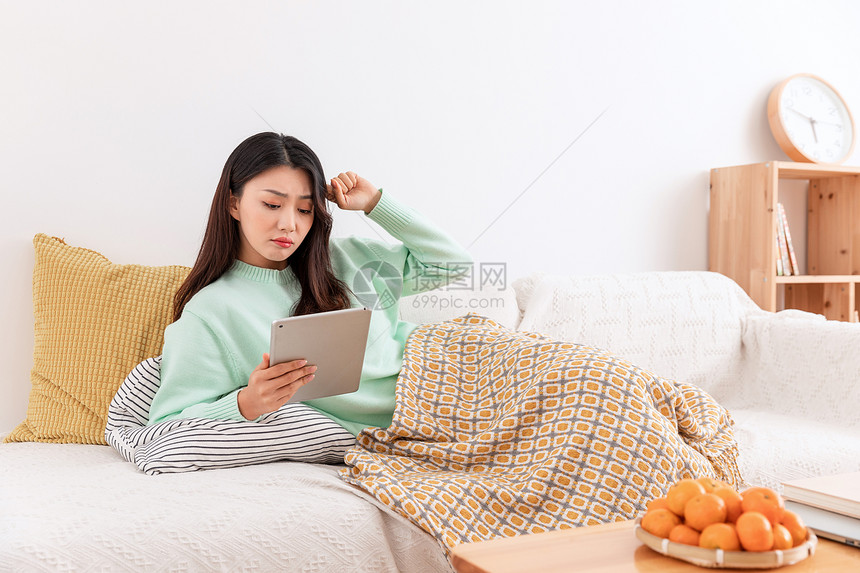冬季美女居家躺在沙发上玩平板电脑图片