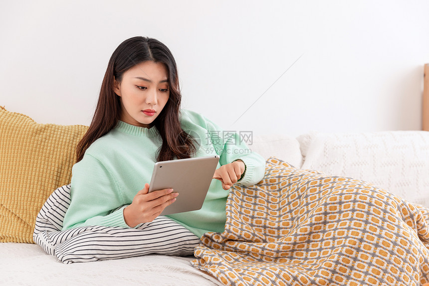 冬季美女居家躺在沙发上玩平板电脑图片
