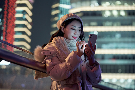 手机美颜夜晚使用手机自拍的冬季女性背景