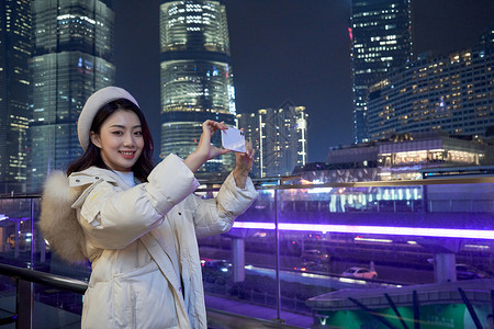 亚洲模式使用手机拍夜景的都市女性背景
