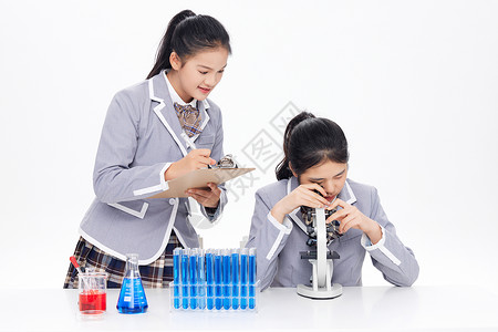 显微镜儿童记录实验数据的青少年女学生背景