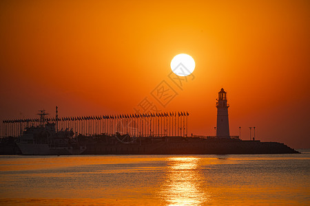 来自后面光线日出时红彤彤的海和伫立的灯塔背景