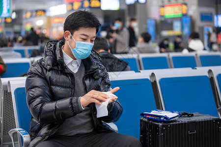 疫情期间男性在火车站时候湿巾擦手冬季高清图片素材