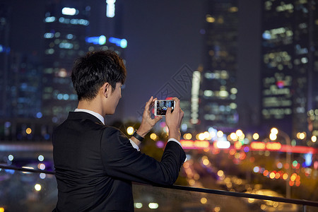 秋冬城市夜晚男青年用手机拍摄背景