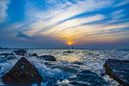 海浪拍打沙滩青岛胶州湾夕阳晚霞海上日落背景