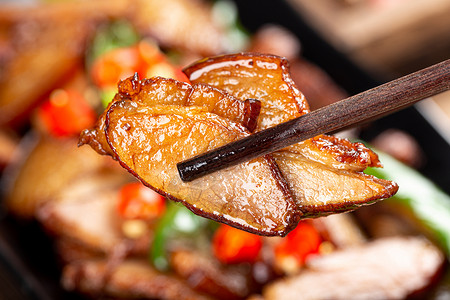 蕨菜炒腊肉筷子夹起一片辣椒炒腊肉背景