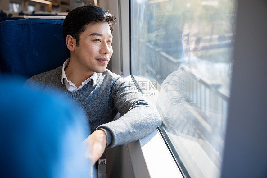 坐在火车上的男性看着窗外风景图片