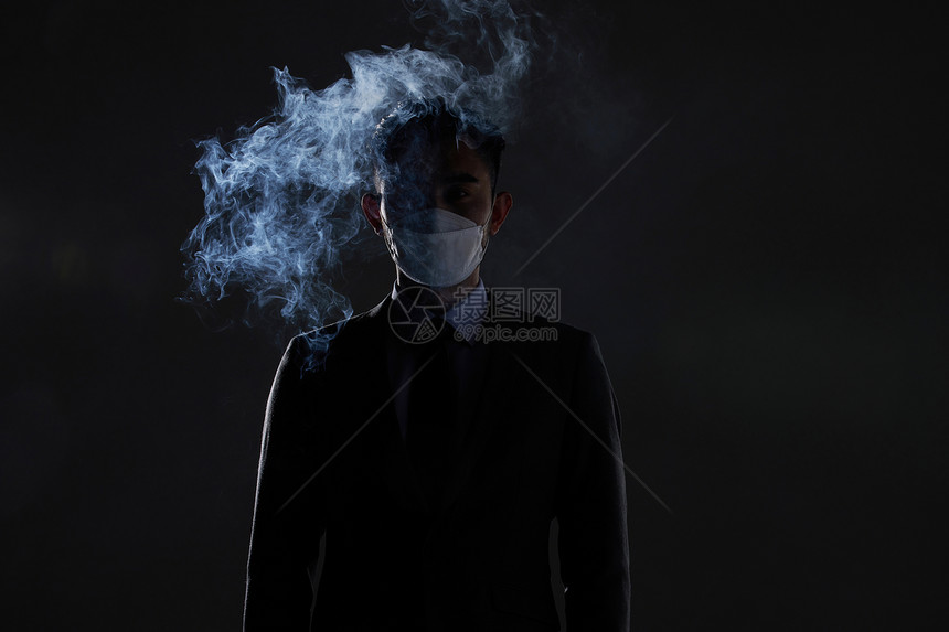 戴着口罩站在烟雾中的男性图片