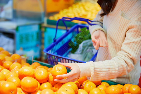 挑选水果年轻女性超市挑选购买橙子背景