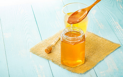 美味蜂蜜蓝色桌上的蜂蜜和蜂蜜水背景