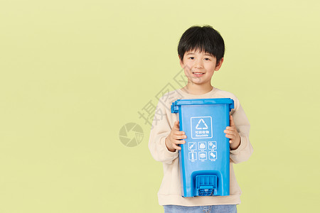 抱着可回收物垃圾桶的小男孩背景图片