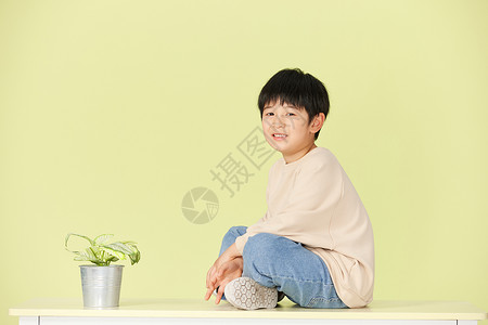 地球上绿植坐在桌子上的小男孩背景