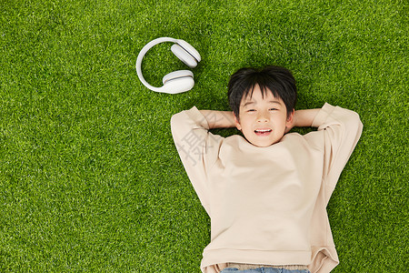 听歌的男孩开心的在草坪上休息的小男孩背景