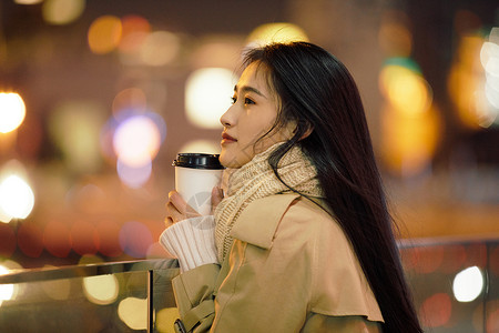 冬季夜晚都市女性手握咖啡杯侧脸高清图片